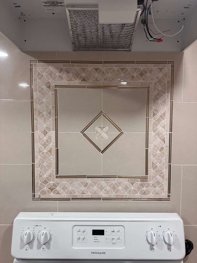 Close-up of the marble mosaic medallion with a diamond center set into the backsplash above the range
