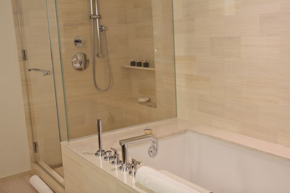 Master bath at The Setai with marble walls, a glass-enclosed shower and a marble tub surround