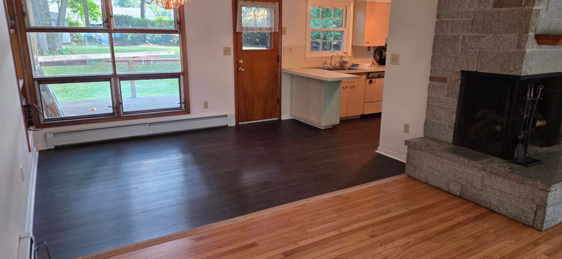 Dark wood-look luxury vinyl plank floor in a dining area, meeting the oak floor of the living room