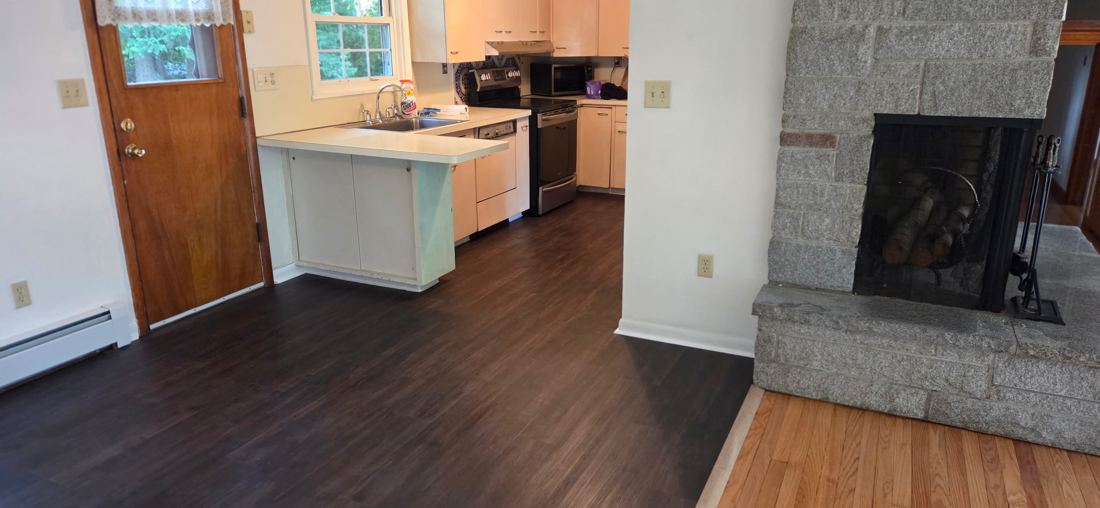 The same dark vinyl plank floor running from the dining area into the kitchen